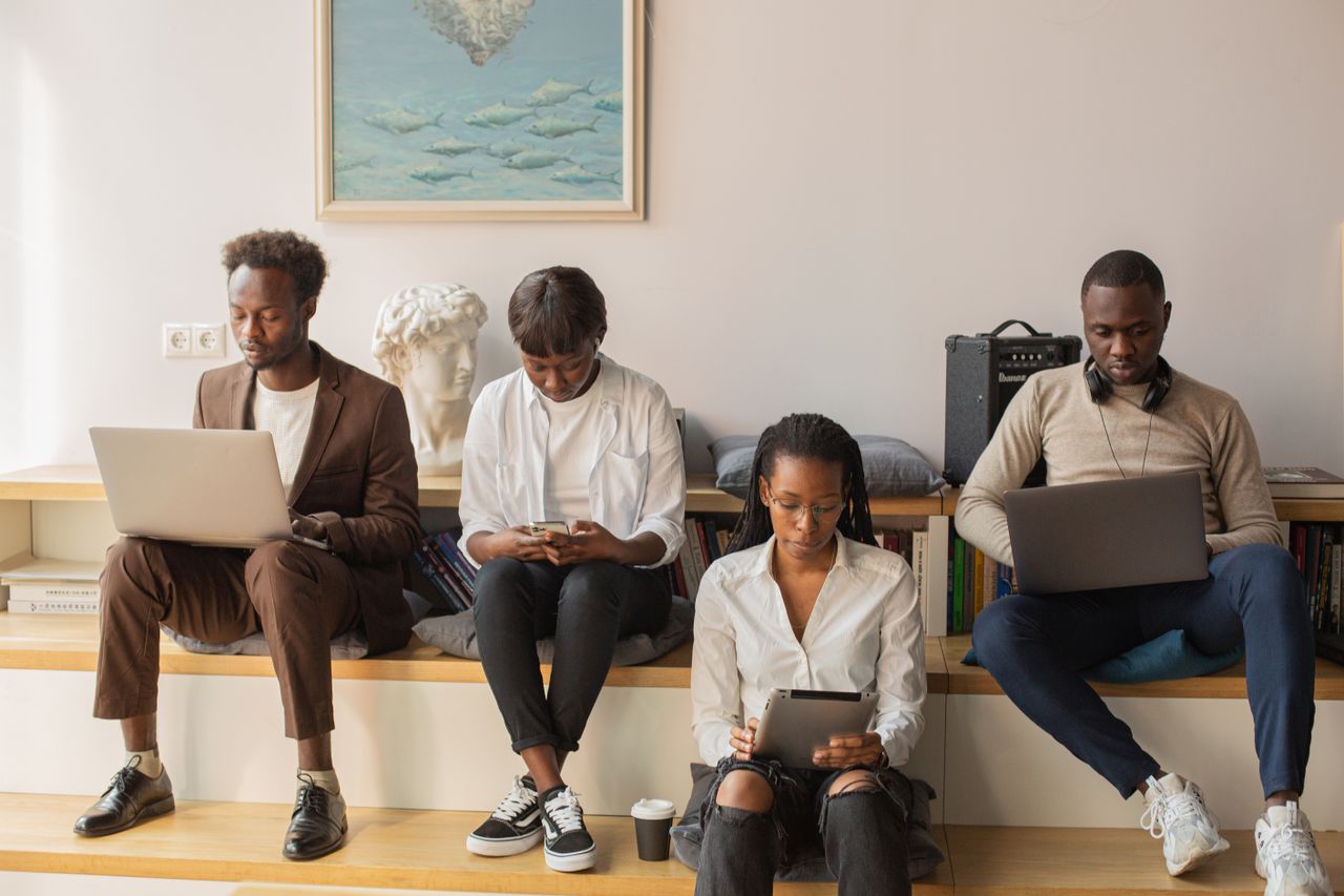 A group of diverse professionals using technology indoors, focused and engaged in a modern workspace.